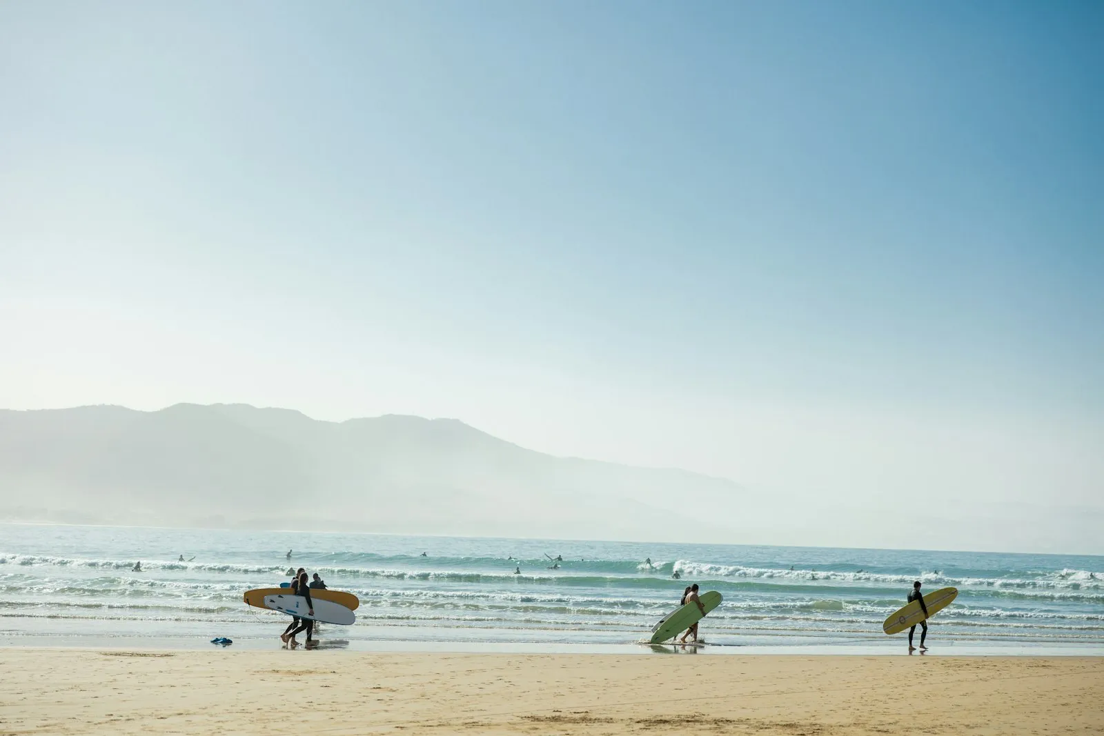 A crew carrying surfboards across the beach at Imsouane