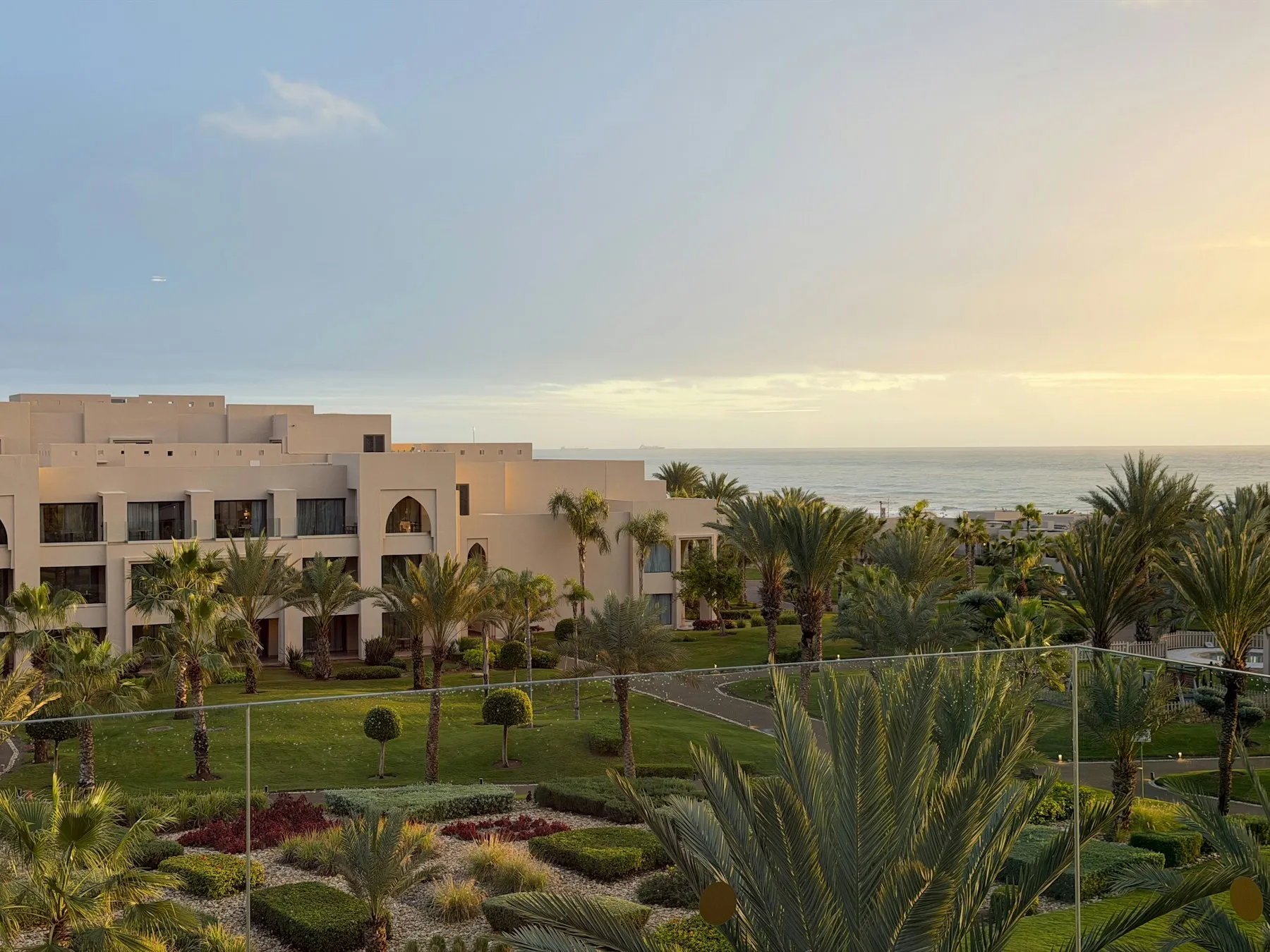 Palms and rooftops glowing at golden hour above the sea in Taghazout
