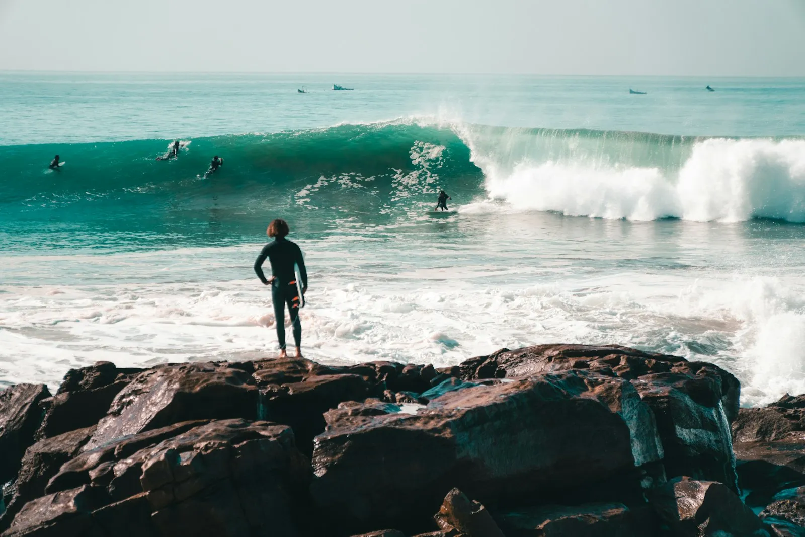 A lone surfer on the rocky shoreline of Anchor Point, Taghazout